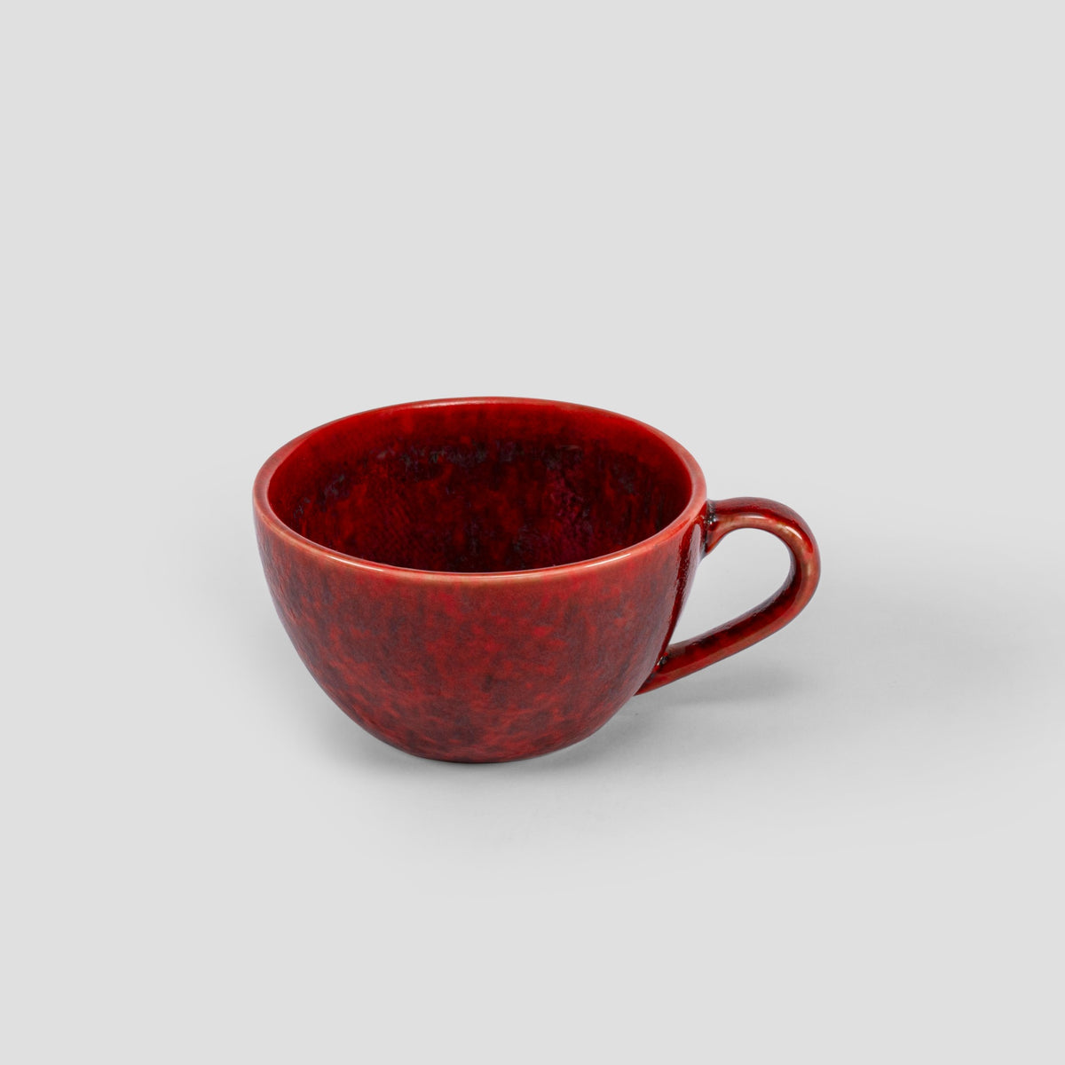 Homura porcelain cup showing the natural depth and variation of its red glaze